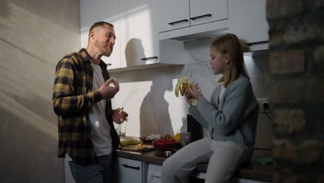 padre e hija comiendo plátanos en la cocina