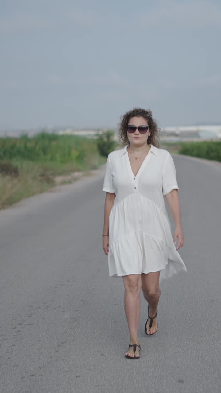 Woman in white dress walking on a road