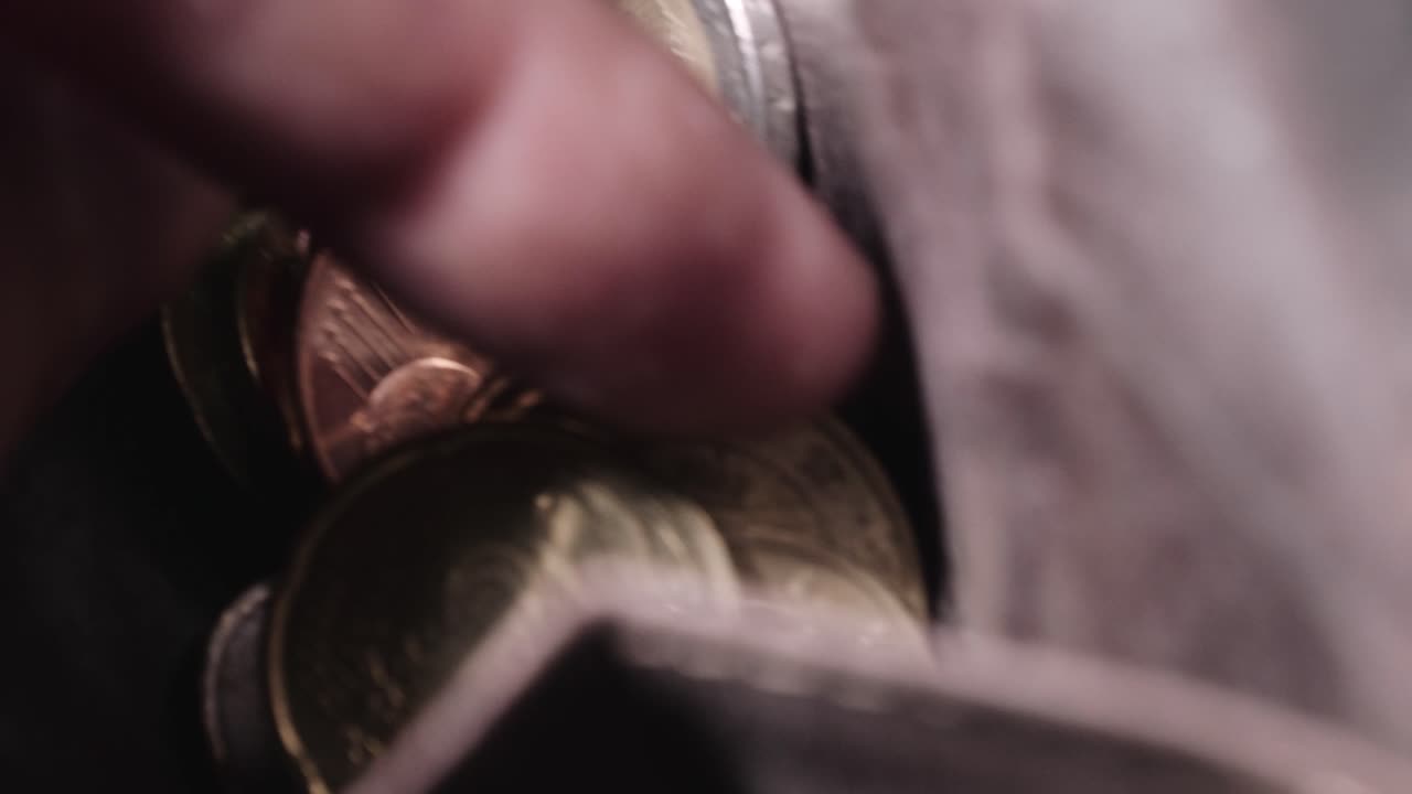 un hombre está mirando a través de una billetera llena de monedas de euro
