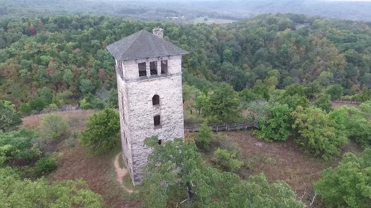 Drone doing a 60 degree rotation around watchtower at Haha Tonka state park with epic scenery of autumn colored trees and sky in background