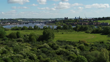 Aerial-push-over-reveal-from-a-river-bank-on-the-river-Medway-to-a-view-of-Rochester-Castle,-Cathedral---Town