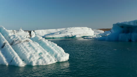 Drone-view-orbit-iceberg-cracked-from-Breidamerkurjokull-glacier-floating-over-Jokulsarlon-lake.-Climate-change-and-global-warming.-Environmental-issue.-Vatnajokull-national-park