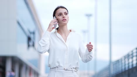 una mujer de negocios está caminando y hablando en su teléfono celular
