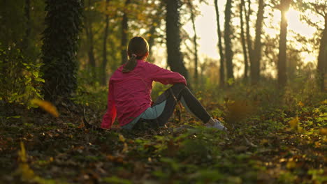 a woman resting in an autumn forest at sunset