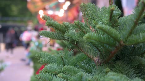 a close-up focus detail on christmas pine trees for home decoration are seen for sale as pedestrians walk by in the background in hong kong