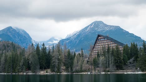 wide 4k shot of hotel patria at štrbské pleso, with snowy tatra mountains, pine forest, and calm alpine lake—ideal for travel, nature, resort, and landscape footage