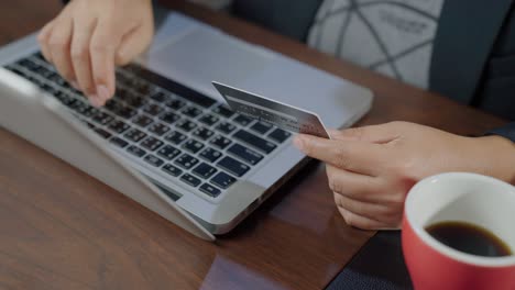 b rodar el movimiento lento de la mano escribiendo el teclado y haciendo compras en línea mientras sostiene la tarjeta de crédito. el titular de la tarjeta sostiene la carta de crédito haciendo pago en línea de e-bank. pagar por la compra en la tienda web usando una computadora portátil