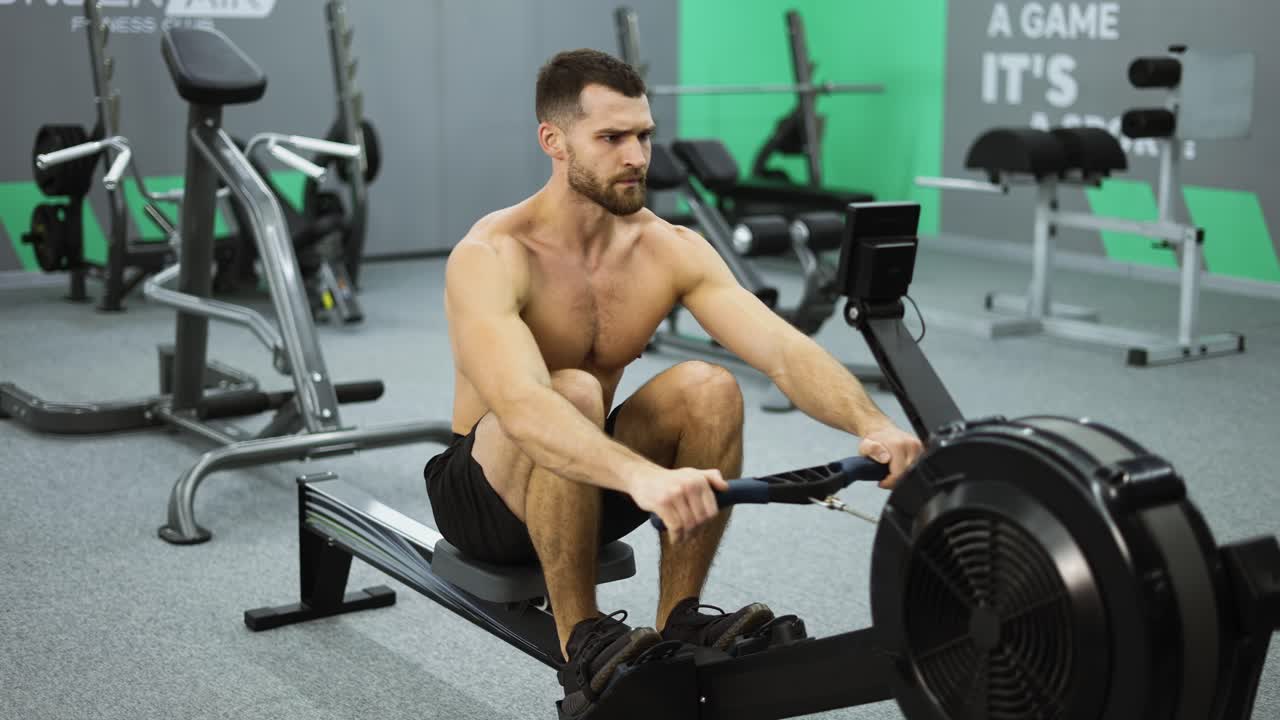Fitness man athlete training rowing machine exercise intense endurance workout