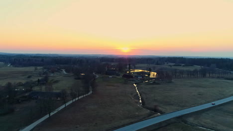 aerial drone shot over water canal surrounded by rural landscape beside road network during sunrise