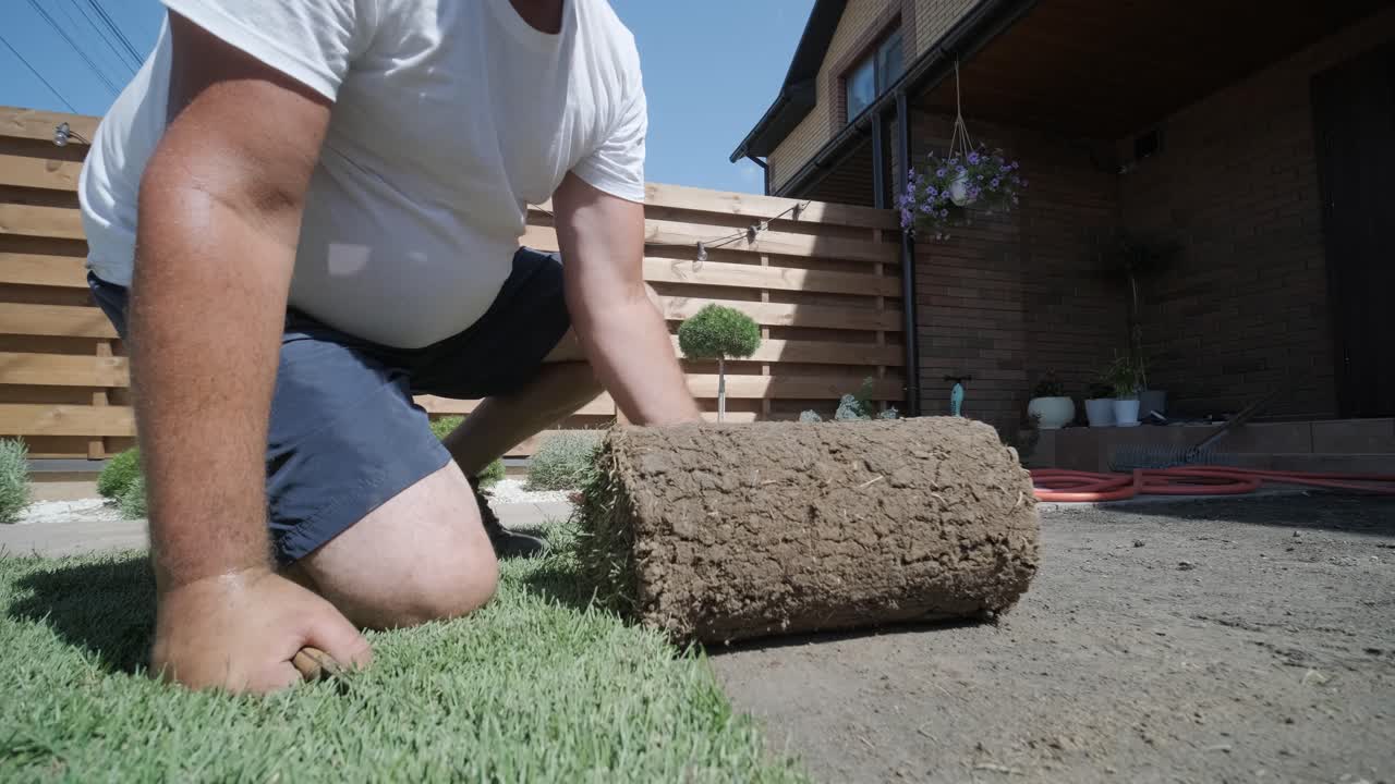 jardinero colocando césped en el patio privado con valla de madera