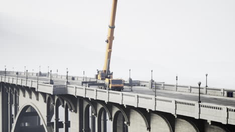 a yellow crane on a bridge under a foggy sky