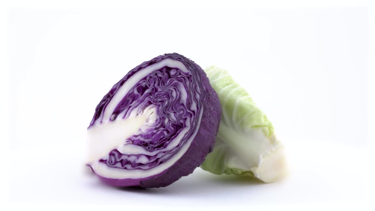 sección transversal macro disparo de dos mitades de mini repollo. uno es blanco y el otro es de color rojo. girando lentamente en la mesa giratoria aislada en el fondo blanco. primer plano.