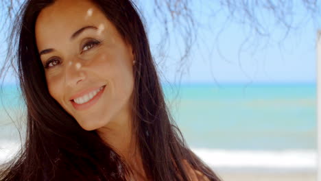 mujer bajo un paraguas de playa sonriendo a la cámara