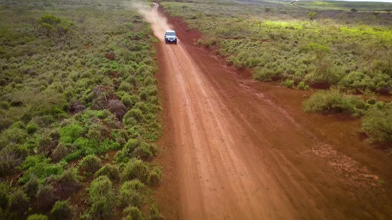un jeep plateado conduce rápido a lo largo de un camino de tierra roja en la isla de lanai en hawaii 2
