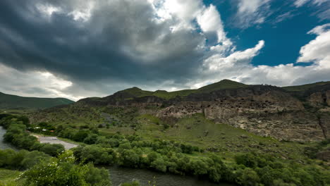 Morning-sun-breaks-through-clouds-over-Vardzia,-ancient-cave-city,-tourist-destination-southern-Georgia,-GE---Timelapse