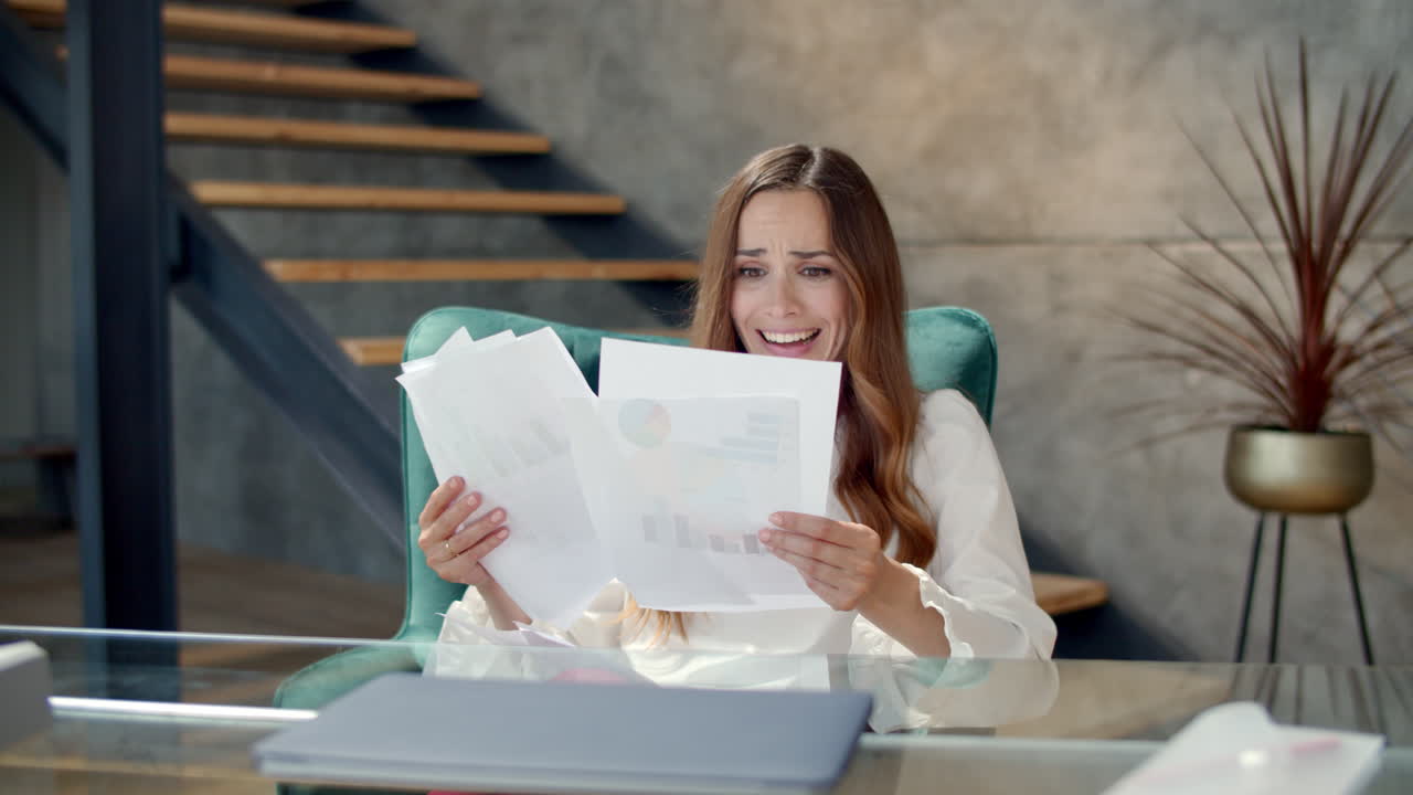 Happy businesswoman looking at graphics in office. Woman throwing papers away.