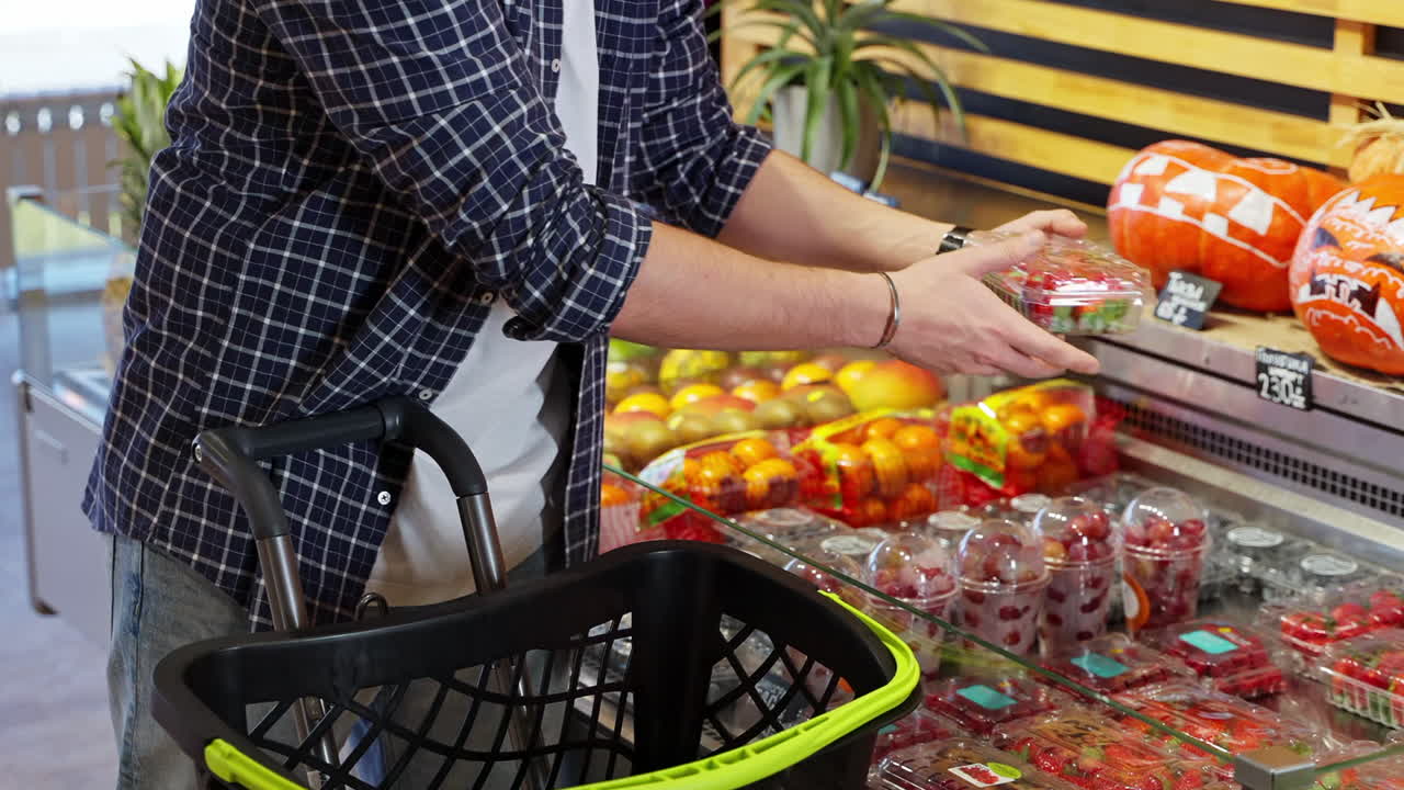 hombre comprando fresas en una tienda de comestibles