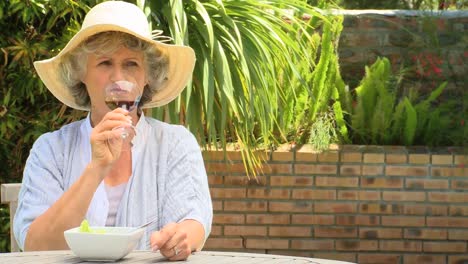 mujer madura bebiendo un vaso de vino tinto al aire libre
