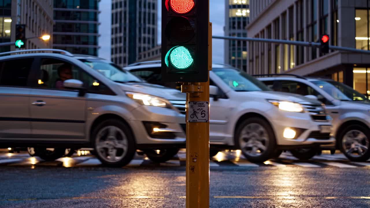 Urban traffic scene at dusk with a focus on a green traffic light