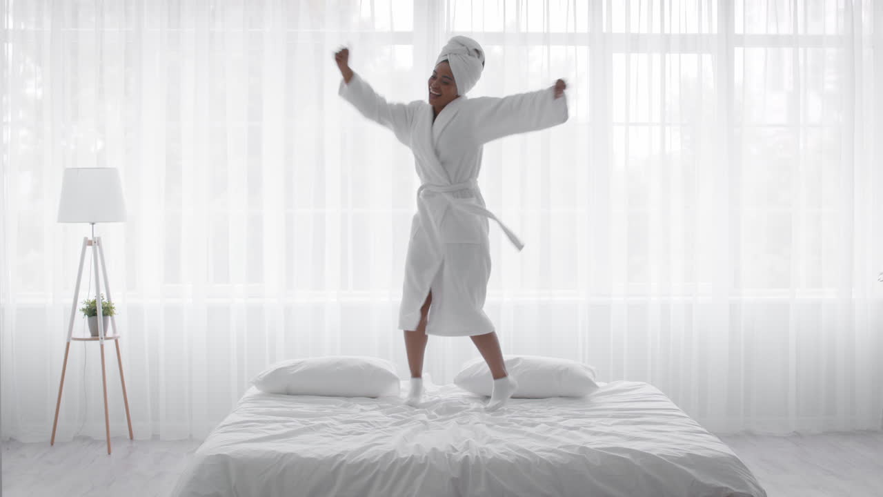 Happy Woman Dancing on Bed in Bathrobe