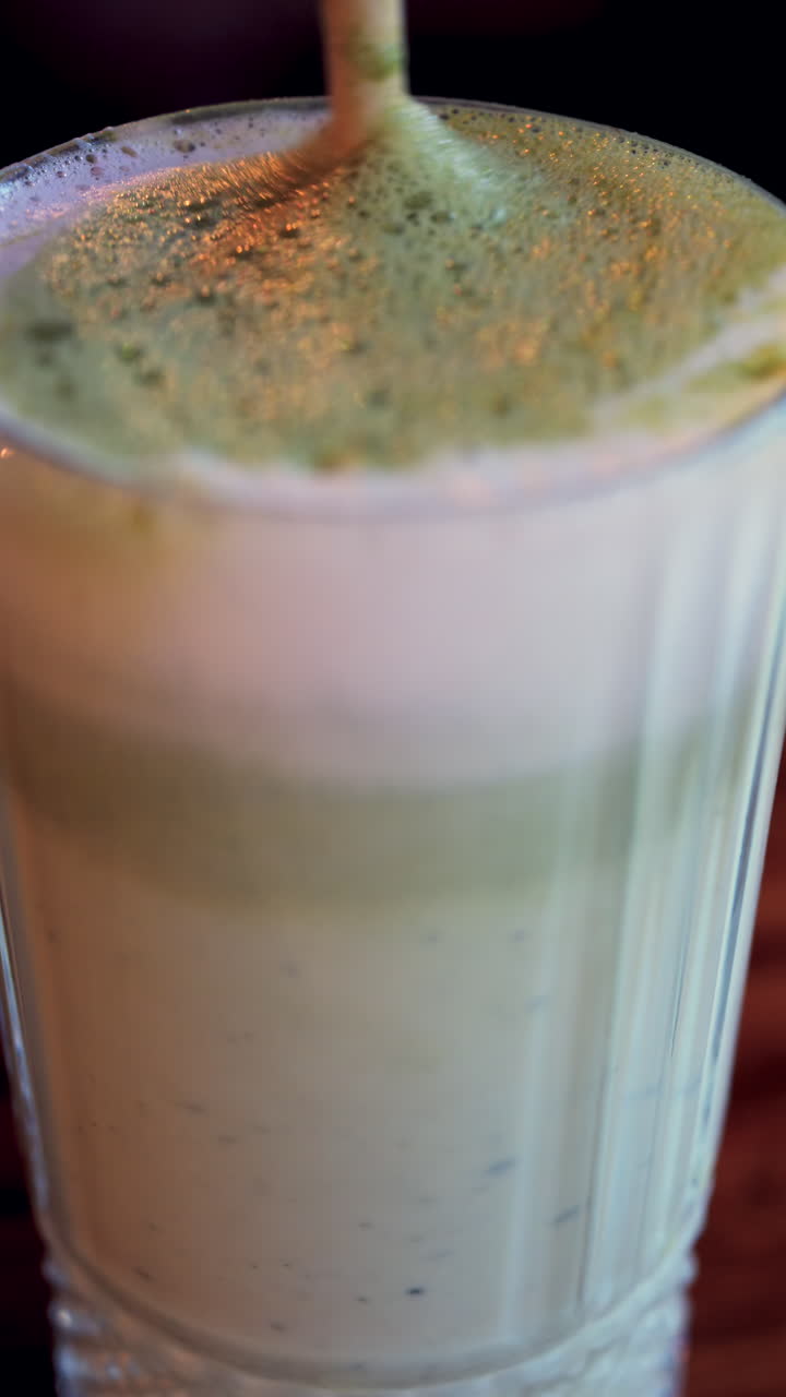 Primo piano di una cannuccia in un matcha latte su un tavolo in un bar. Verticale