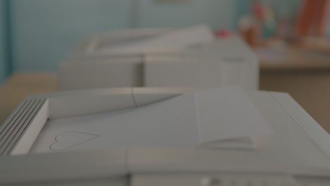 Two-Old-90's-Printers-Printing-Love-Hearts-on-A4-Paper,-Static-Close-Up-Shallow-Focus