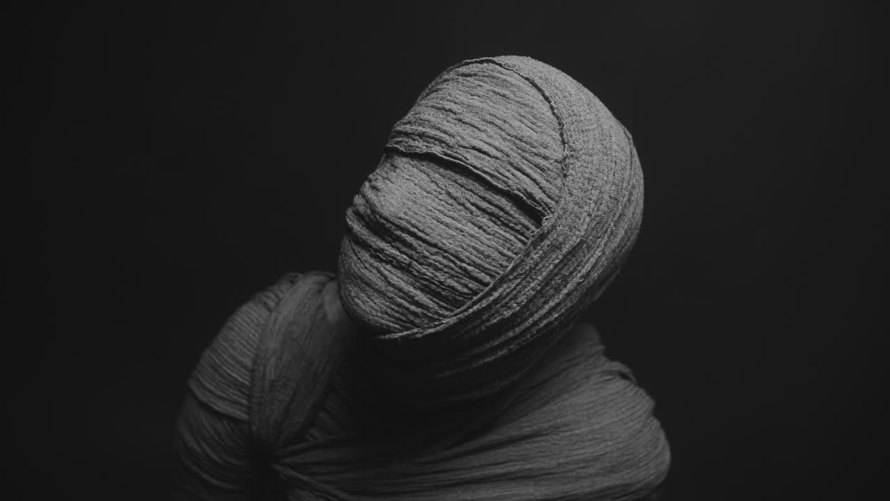 A mummy of a woman on a dark backdrop rises her head