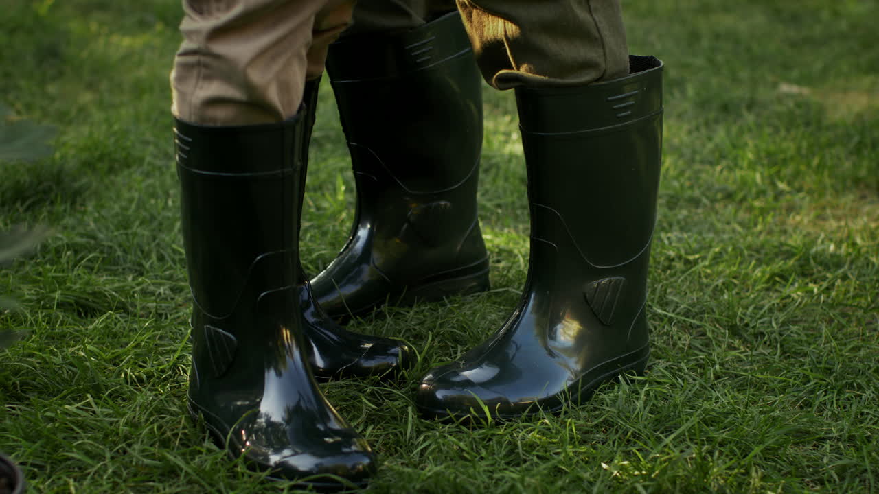 Child and adult wearing rain boots in grass