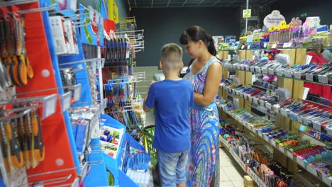 vinnitsa, ukraine - august, 2018: back to school concept. young mother and little boy buying school supplies in store