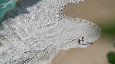 Una-Pareja-Joven-Se-Para-Frente-A-Una-Gran-Rompiente-En-La-Costa-De-Grandes-Olas-En-Una-Isla-Tropical