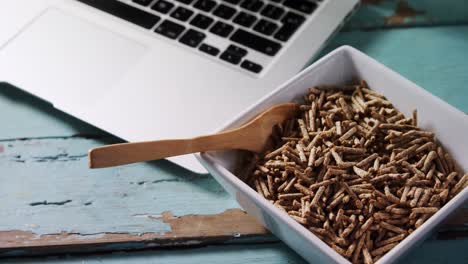 cuenco de palitos de salvado de cereal con cuchara y computadora portátil 4k