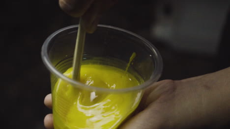 thick viscous epoxy resin being stirred in plastic bowl