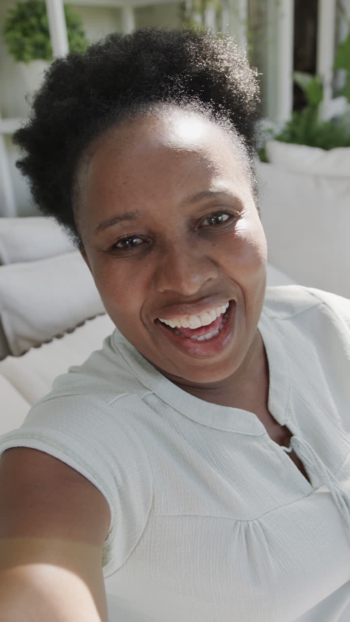 Vertical video of portrait of happy senior african american woman having video call in slow motion