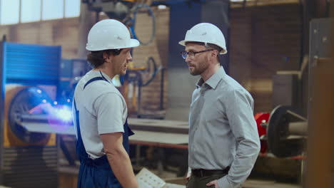 factory worker shaking hands and discussing tasks with engineer