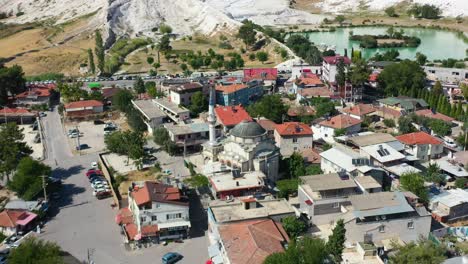 aerial top down view of a small town with residential buildings in pamukkale turkey and mineral rich mountain hills in the distance