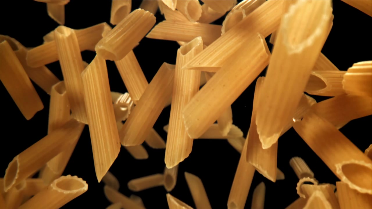 Primo piano di penne che cadono al rallentatore su sfondo nero