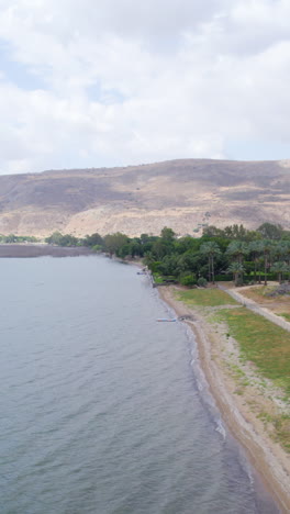the sea of galilee and the golan mountains in a cloudy summer afternoon - arial sliding vertical shot