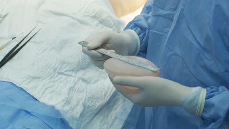 the surgeon prepares a sterile silicone breast implant for breast augmentation surgery