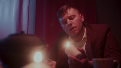 man lighting a candle in a dimly lit room