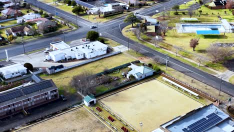 drone footage captures a bright, daytime aerial view of coonabarabran’s residential streets, buildings, and sports fields, with smooth forward camera movement and clear lighting