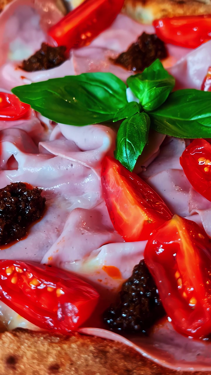 Fette di mortadella con basilico e pomodorini e marmellata spalmata su pane o pizza, verticale