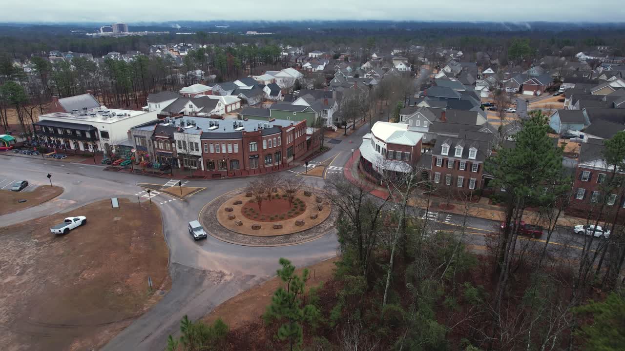 Aerial pull away of small town shops and roundabout in front of suburban area at Moss Rock Preserve in Hoover, Alabama