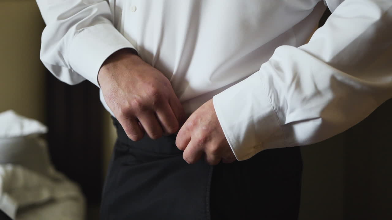 novio poniéndose los pantalones y preparándose para el día de su boda