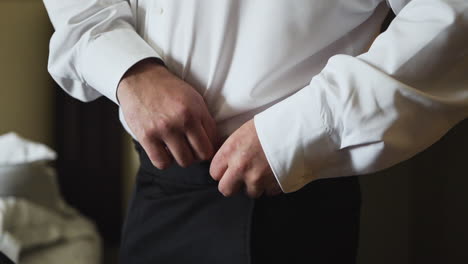 groom putting pants on and getting ready on his wedding day