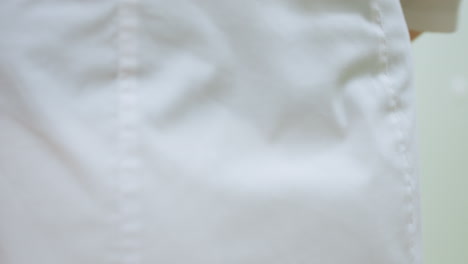 back view of medical personnel in white uniform walking down hallway to door opens it slowly then shuts it behind her creating calm and professional atmosphere inside clean clinical environment