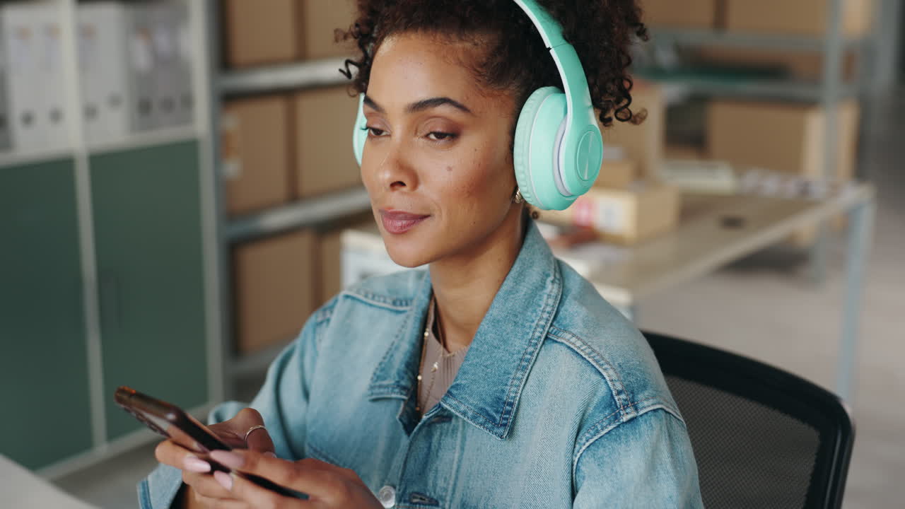 Woman using phone with headphones in office