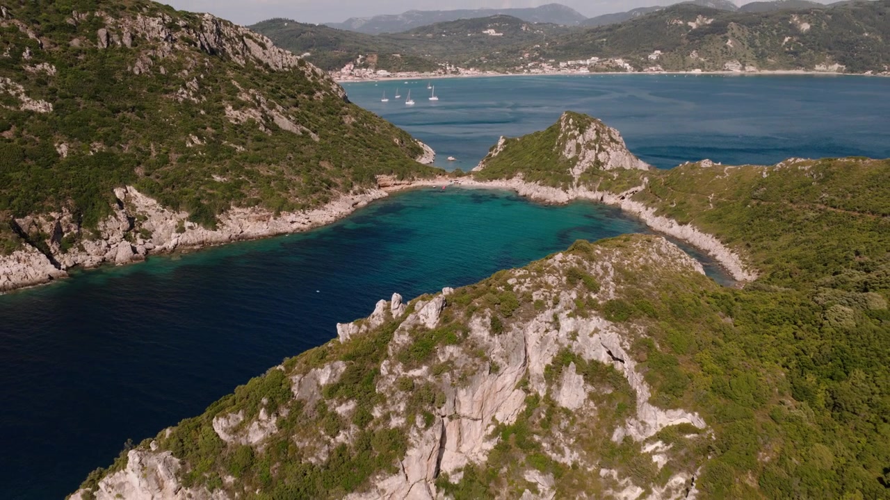 Vista drone delle baie gemelle di Porto Timoni con acque ioniche cristalline.