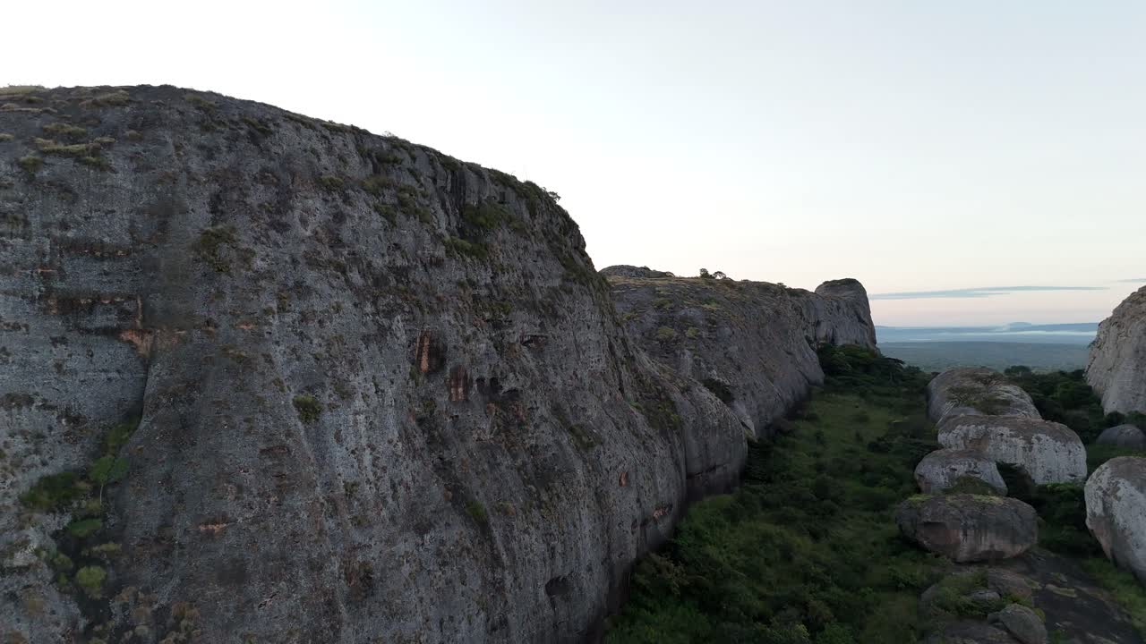 Volo cinematografico con drone attraverso gli antichi giganti di pietra di Pedras Negras in Angola, che cattura il drammatico contrasto tra le rocce scure e la vivace pianura in una destinazione di viaggio africana