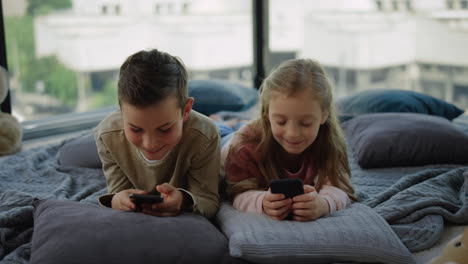 tricky kids addicting mobile games. siblings playing on smartphones at home.