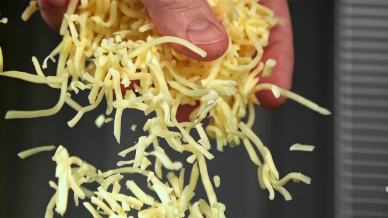 Ripresa al rallentatore di formaggio grattugiato che cade da una mano